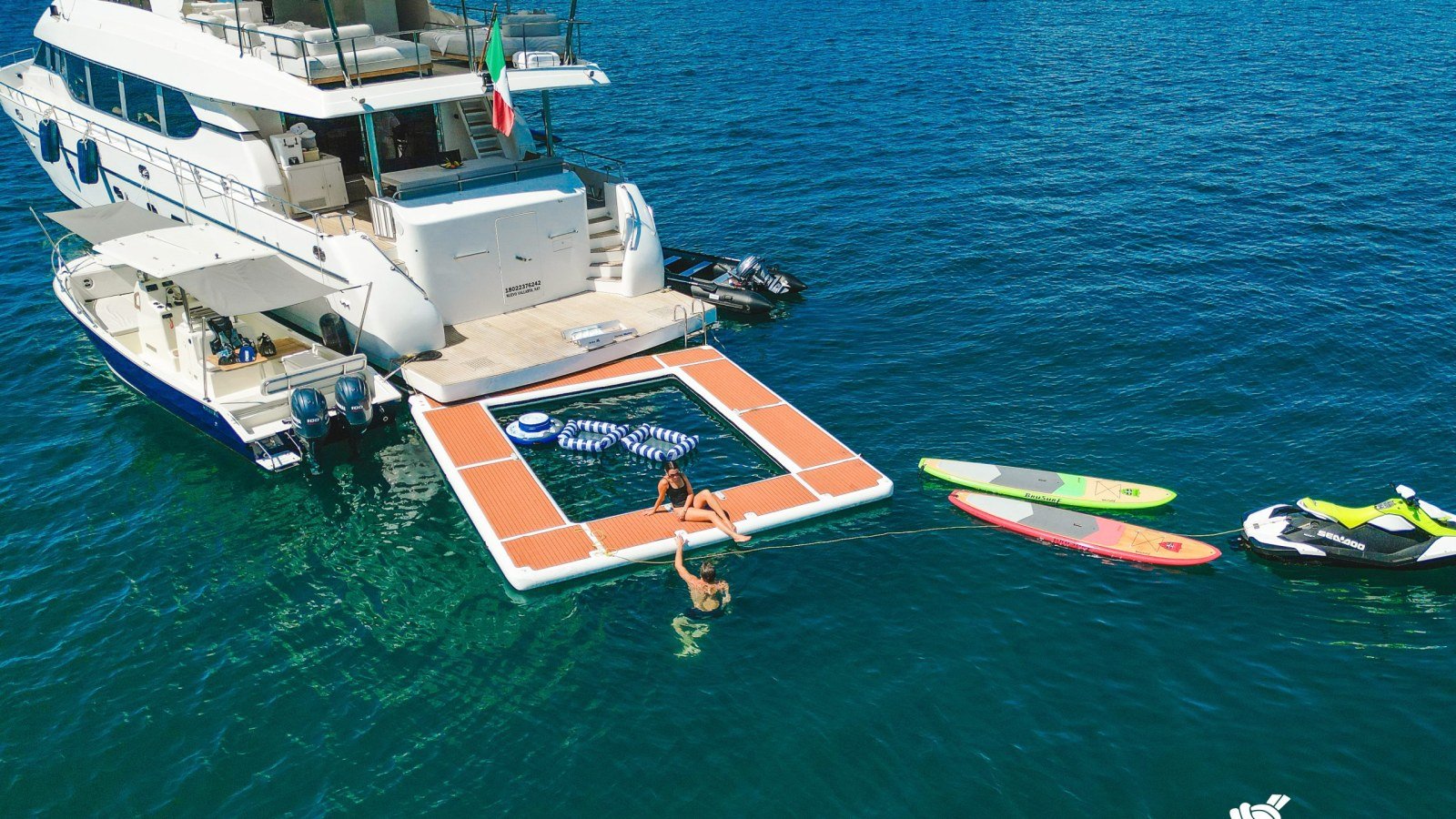 Invitados en una colchoneta flotante y tablas de paddle junto al yate Montefino 84 fondeado frente a la costa de Punta Mita