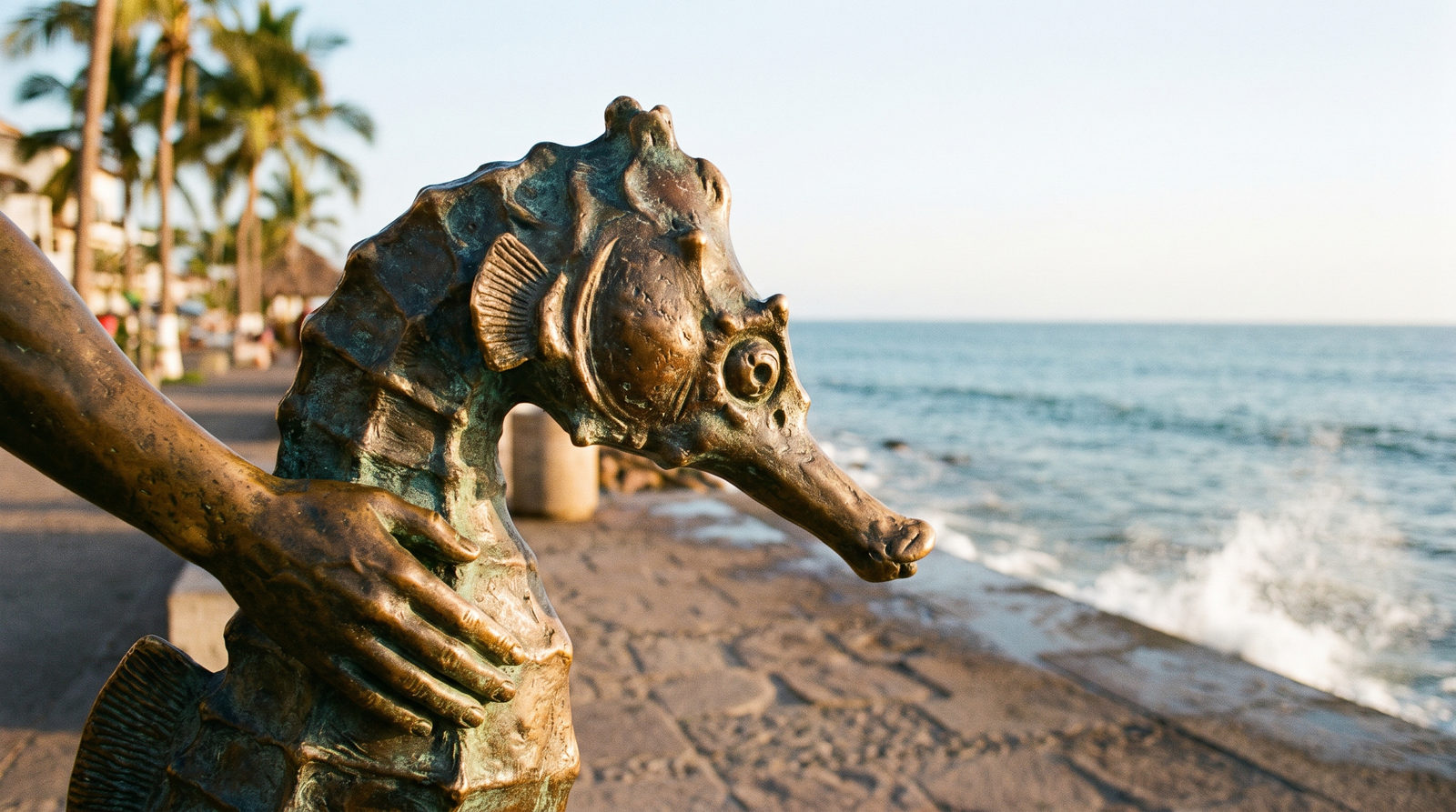 Esculturas y paseantes en el Malecón de Puerto Vallarta al atardecer